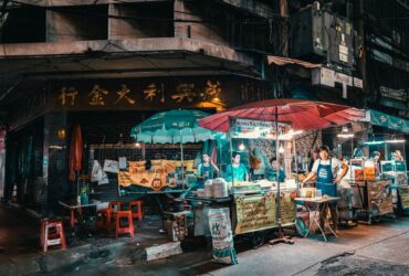 Colorful Thai night market with street food stalls, umbrellas, and vendors at night in an urban setting