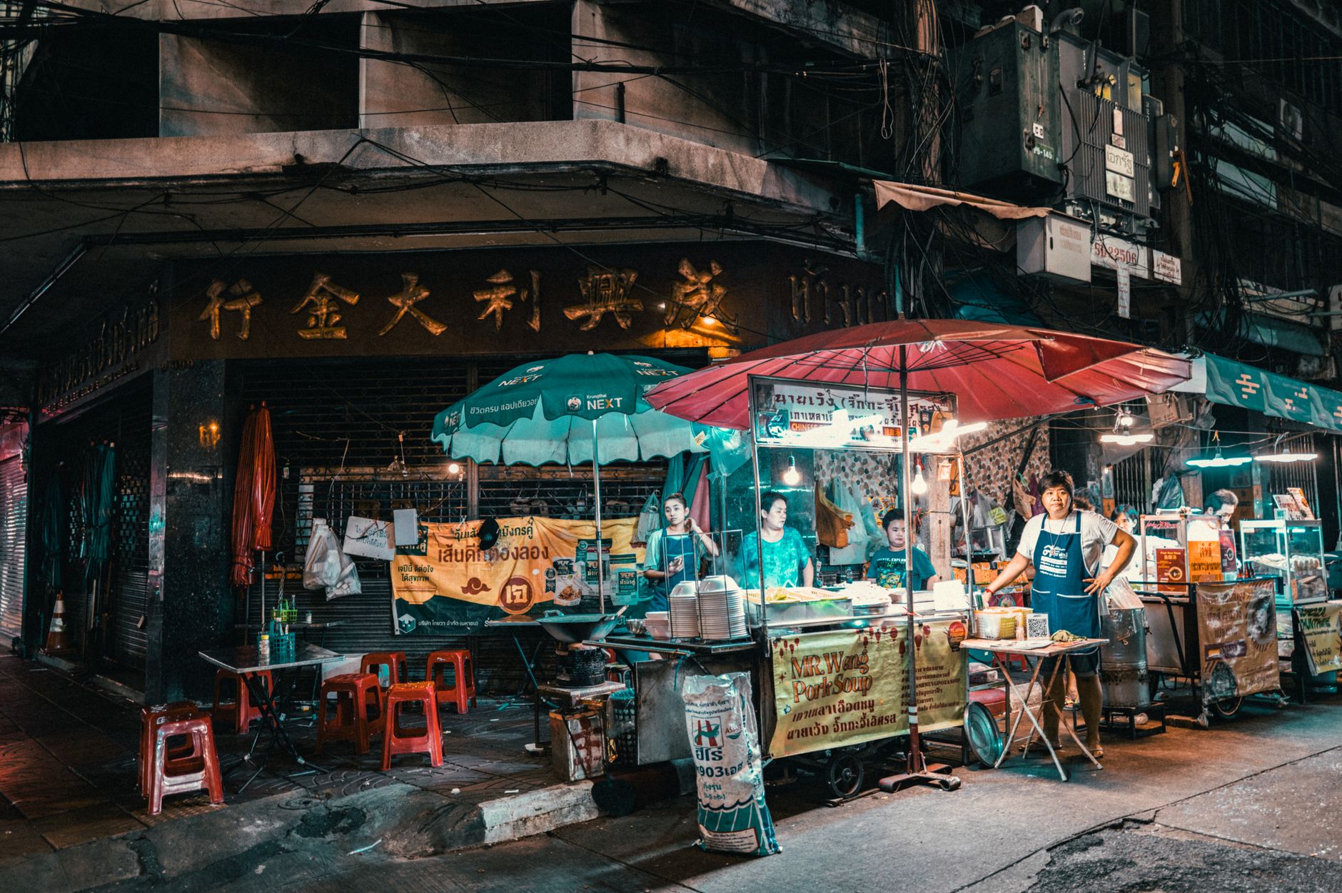 Vibrant Thai night market with glowing food stalls and shoppers in a busy urban street scene
