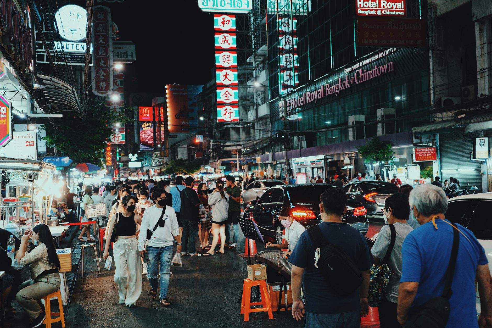 Busy Thai night market street with crowds and vibrant neon signs at night